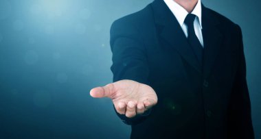Asian Man standing and shows outstretched hand with open palm on Light of Len flare and Boke blue background. COPY SPACE.