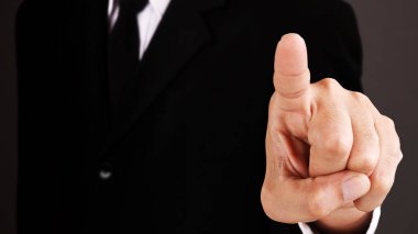 Man without head standing and shows outstretched hand with Pointing Finger on dark background. COPY SPACE.