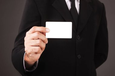 Man in suit holding white business card isolated on gray background