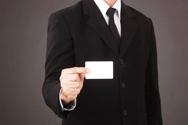 スーツの男灰色の背景に隔離された白い名刺を保持 — ストック写真