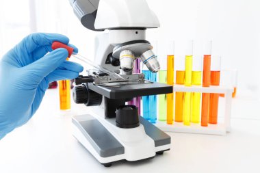 Plaka Mikroskobu 'nu Beyaz Arkaplanda Renk Çözüm Tüpleriyle Test Etmek İçin Bilim Adamlarının Eli Örnekleme Çözümünü Kapat.