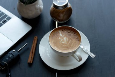 Beyaz bir fincanda iş beklerken kapuçino kahvesi.