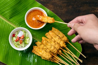 Pork satay - Fıstık soslu ızgara domuz eti ya da muz yaprağında tatlı ve ekşi sos - ahşap masada Asya yemeği tarzı