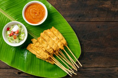 Pork satay - Fıstık soslu ızgara domuz eti ya da muz yaprağında tatlı ve ekşi sos - ahşap masada Asya yemeği tarzı