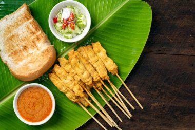 Pork satay - Fıstık soslu ızgara domuz eti ya da muz yaprağında tatlı ve ekşi sos - ahşap masada Asya yemeği tarzı