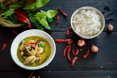 Koyu ahşap zeminde karides ve etli yeşil köri.