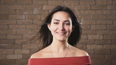 Etkileyici uzun gevşek koyu kahverengi saç, pürüzsüz bir cilt, yuvarlak çene ve derin gözleri ile mutlu on sekiz yaşında bir kız aniden içtenlikle, onun güzel gamzeler ve beyaz dişler Studio, yavaş hareket gösteren gülümsüyor