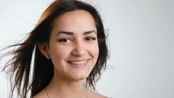 Une jolie adolescente aux beaux cheveux longs en streaming sourit sincèrement et envoie des étincelles de son bonheur à un caméraman, photographié en studion, au ralenti — Video