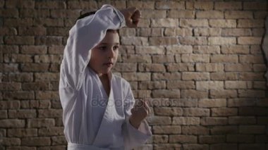 Paracticed karate blok Studio bir beyaz kimono giymiş küçük bir çocuk