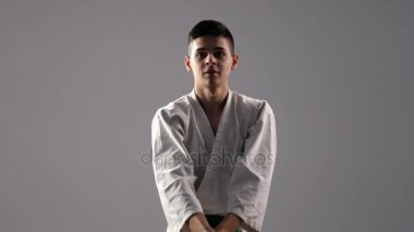 Studio beyaz kimono içinde genç sporcu bir egzersiz antik katana kullanımı