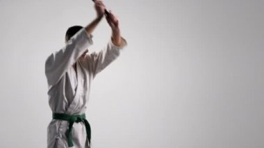 Studio beyaz kimono içinde genç sporcu bir egzersiz Katana kullanımı