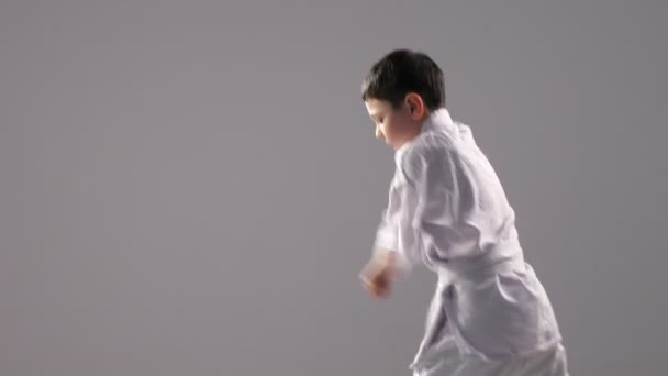 Un karateka joven está de perfil y hace una secuencia de bloques de autodefensa — Vídeo de stock