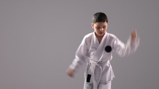 En sju år gammal pojke visar en karate kata, en sekvens av olika ställningstaganden och strejker — Stockvideo