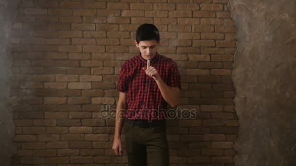 Νεαρό αγόρι καπνίζει ένα ηλεκτρονικό τσιγάρο, κάνει πυκνό καπνό ρέματα και λευκούς κύκλους γύρο στο slo-mo — Αρχείο Βίντεο