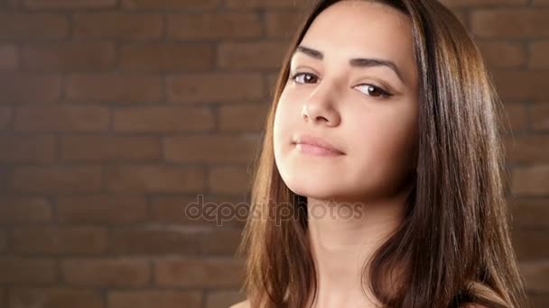 Una joven con un hermoso cabello castaño le da la mano y sonríe felizmente — Vídeo de stock