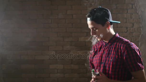 Young boy uses an e-cigarette and breathes out two smoke rings at once in slo-mo — Stock Video