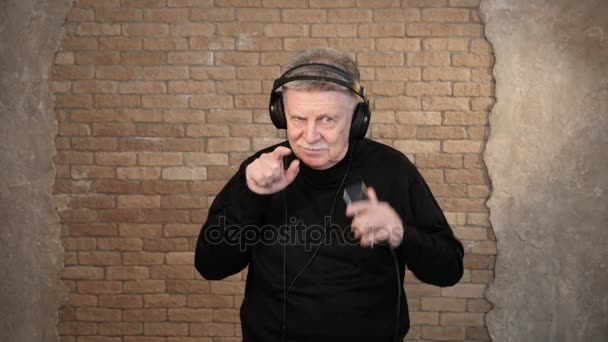 Starszy człowiek słucha muzyki, będąc w słuchawki i tańce energicznie — Wideo stockowe