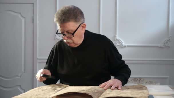 A senior man explores some ancient Torah or Talmud manuscript with a head lens — Stock Video