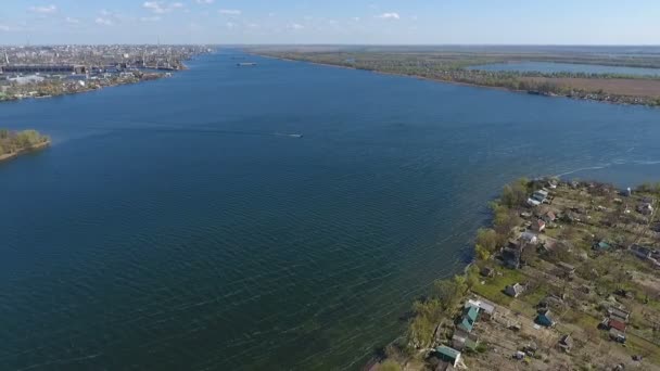 Повітряний постріл берега річки з невеликими літніми котеджами на ньому і розкішними водами — стокове відео