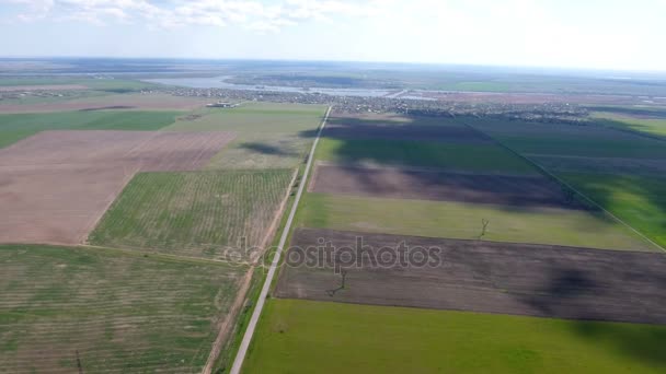 Tiro aéreo de uma paleta de campos agrícolas que levam a uma margem de rio — Vídeo de Stock