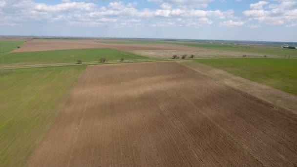 Tiro aéreo de um campo arado marrom que leva a uma estrada rural na primavera — Vídeo de Stock