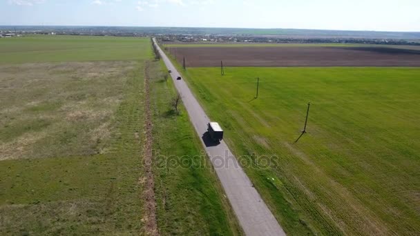 Vue aérienne d'un camion et d'une voiture se déplaçant le long d'une route de campagne le long des champs 