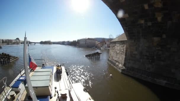 Prag, Tjeckien - 24 mars, 2017:Motorboat flyttar under vissa stenbro i Prag i en solig dag på våren — Stockvideo