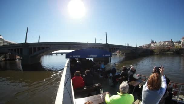 Prague, République tchèque - 24 mars 2017 : Un bateau à moteur avec des gens se déplace sous un pont à Prague par une journée ensoleillée au printemps — Video