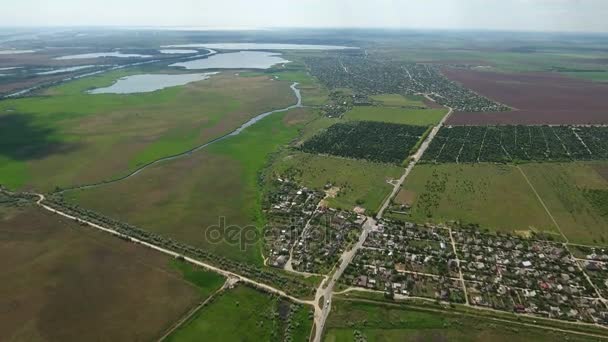 Аэросъемка небольшой деревушки в Восточной Европе с зелеными полями, озерами поблизости — стоковое видео