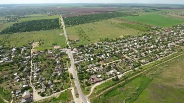 Foto aérea de un pequeño pueblo en Ucrania situado entre los campos verdes en primavera — Vídeos de Stock