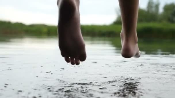 Щасливі жіночі ноги гойдаються над деякими озерними водами з зеленою тростиною в шлю-мо — стокове відео