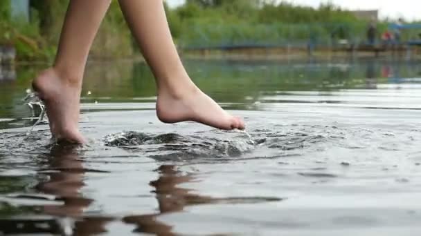 Ženské nohy jsou kyvné přes některé vody jezera v uvolněné způsobem zpomaleně — Stock video