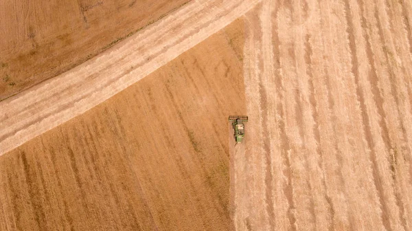 Aerial shot of an agricultural wheat field and a combine harvester  in Europe Royalty Free Stock Images