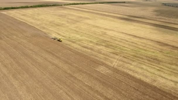 Tiro aéreo de un campo ucraniano y un tractor de granja tirando de una grada en verano — Vídeo de stock