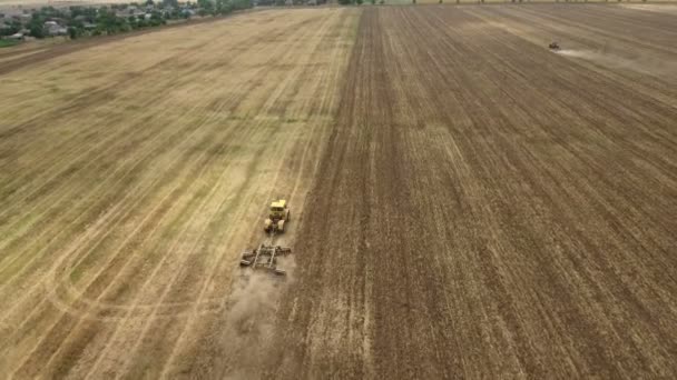 Tiro aéreo de un campo ucraniano y un tractor grande tirando de una grada en verano — Vídeo de stock