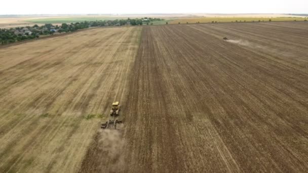 Aerial shot of a Ukrainian field and a farm tractor pulling a harrow in summer — Stock Video