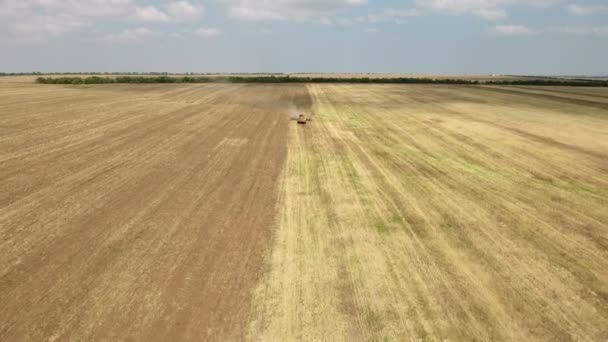 Foto aérea de un campo agrícola y un tractor grande tirando de una grada en verano — Vídeos de Stock