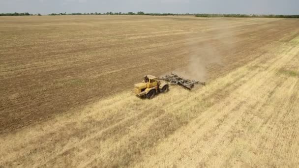 Воздушный кадр безграничного поля и большой трактор, тянущий борону летом — стоковое видео