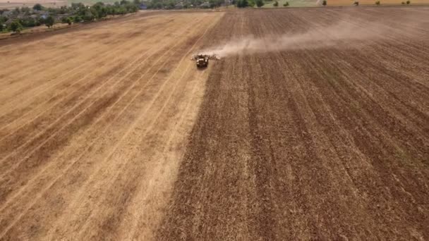Aerial shot of an agricultural field and a big tractor pulling a harrow in autumn — Stock Video