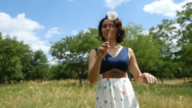 Genç kadın bir karahindiba ile dalgalar ve onun uçan tohum slo-mo bakar