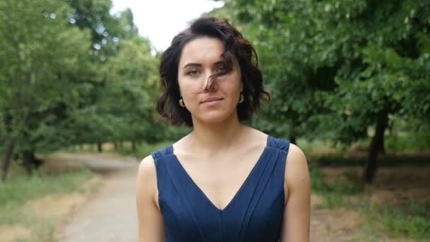 Young woman with wavy hair goes along a country road in summer in slow motion — Stock Video