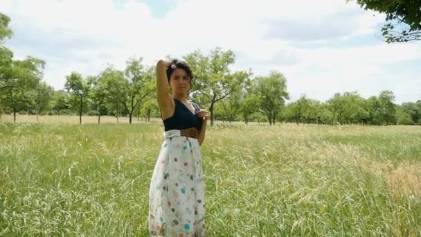 Junge Frau steht und hält ihre Haare romantisch auf einer Liegewiese im Sommer in Slo-mo — Stockvideo