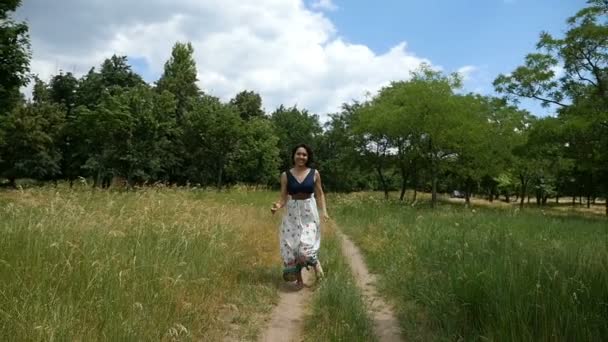 Блаженна брюнетка біжить по сільській дорозі в сільській сукні в шлю-мо — стокове відео