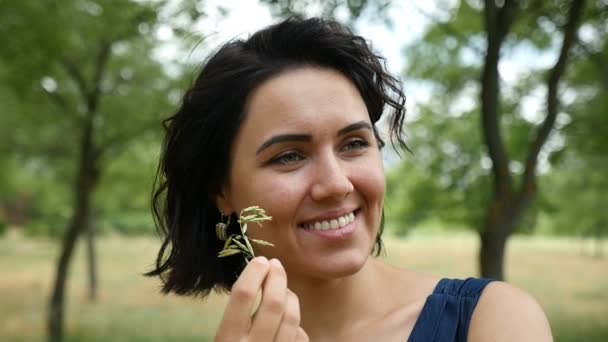Молода жінка бере дику траву в рот і посміхається бути щасливою в шлю-мо — стокове відео