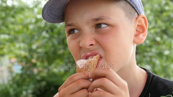 Eight year old boy eats ice cream on a sunny day in summer in slow motion — Stock Video