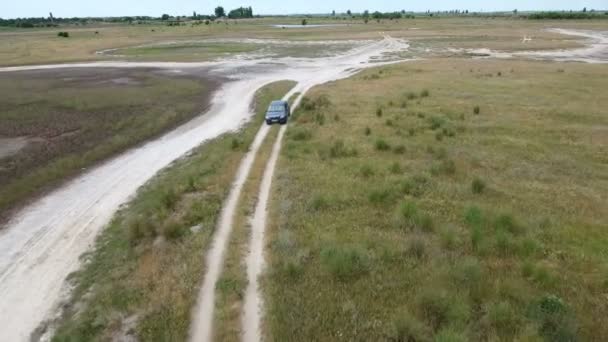 Foto aérea de un coche verde que viaja por una carretera sin pavimentar en el Mar Negro — Vídeos de Stock