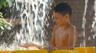 Su Parkı suda streams altında bir sıcak yaz gününde mutlu çocuk duruyor