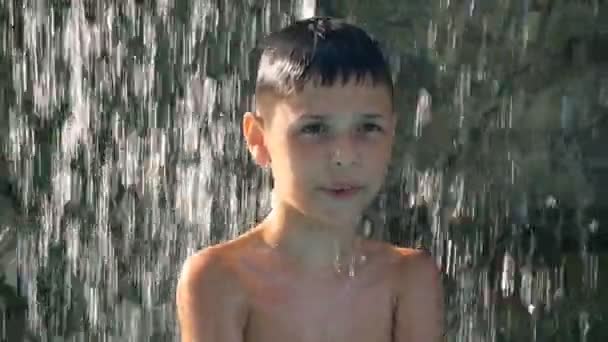 Niño pequeño bailando en la piscina bajo la fuente, consiguiendo gran placer en un día caluroso del verano, no queriendo dejar el frescor del agua — Vídeos de Stock