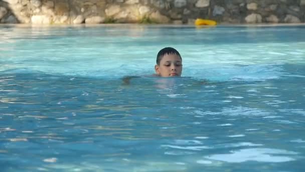 Мальчик с удовольствием плещется в аквапарке бассейна — стоковое видео