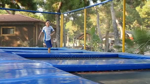 Счастливый школьник любит прыгать на батуте на детской площадке — стоковое видео